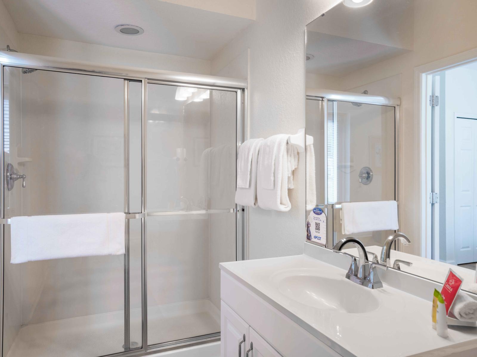 Tranquil white bathroom of the townhouse in Orlando - Space thoughtfully used for a glass enclosed walk-in shower area - Enjoy the availability of bathroom amenities and fresh towels - Lovely vanity completed with a big size wall mirror