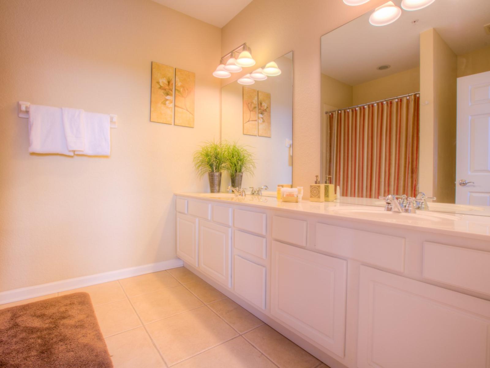 Lavish Bathroom of the townhouse in Orlando - Glorious vanity with twin sinks and large size wall mirrors with wall lamps - Decored with wall paintings - Sufficient storage space -  Availability of fresh towels