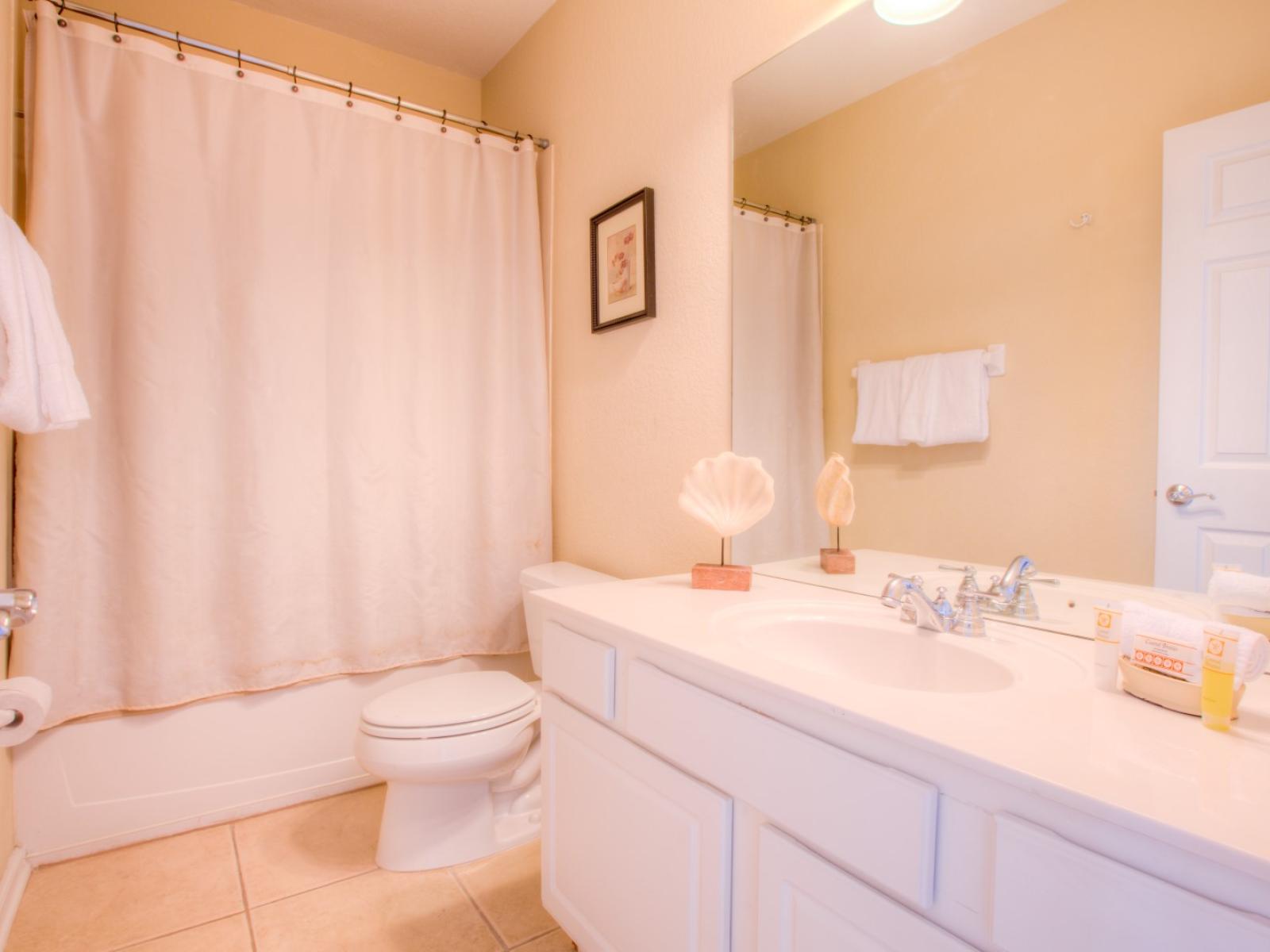 Classy bathroom of the townhouse in Orlando - Neat and clean toilet seat - Beautifully designed bathtub and shower combo area with sliding curtains - Availability of fresh towels and all bathroom amenities - Elegant lighting