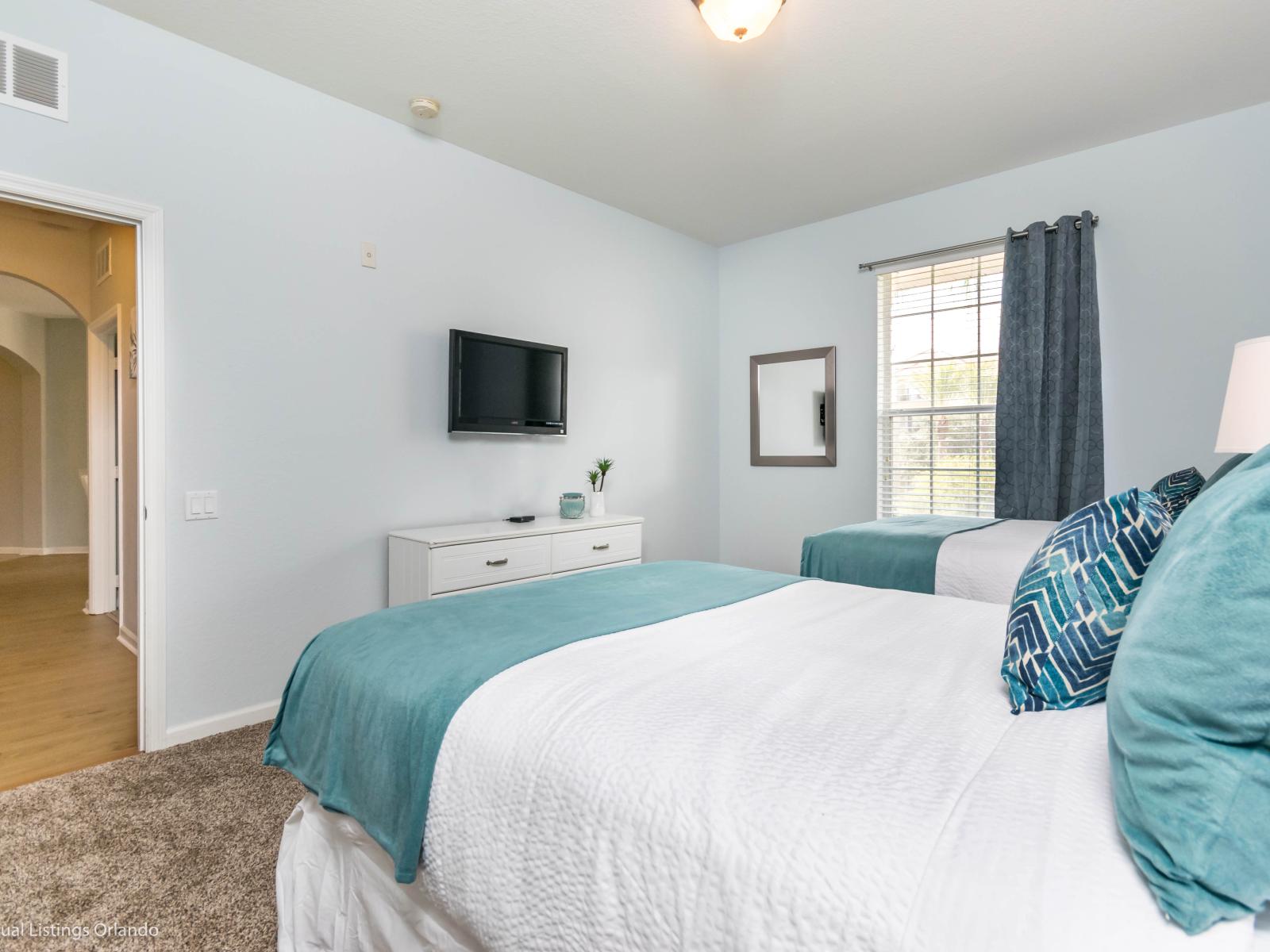 This bedroom with two beds radiates charm and warmth, offering a cozy haven where shared dreams and laughter intertwine, creating cherished memories in a space designed for friendship and fun.