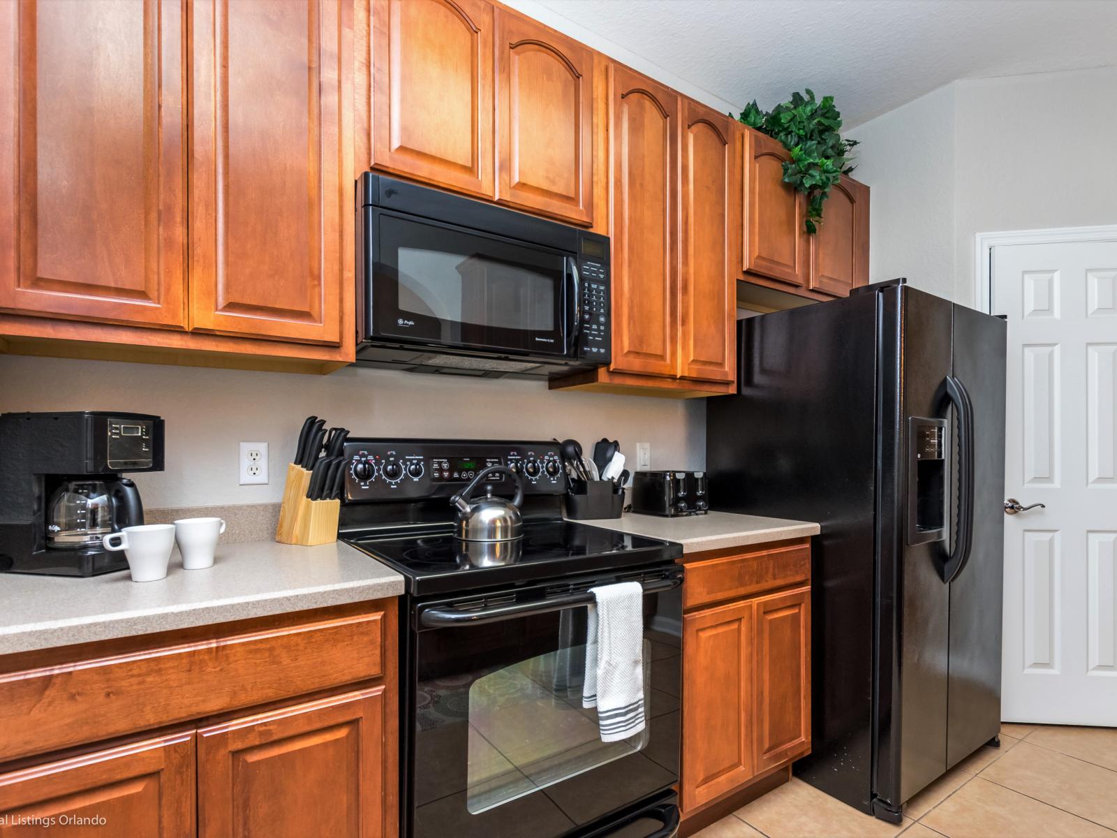 Step into the sleek ambiance of the kitchen, where the harmonious blend of wood and black hues creates a modern and inviting space for culinary adventures.