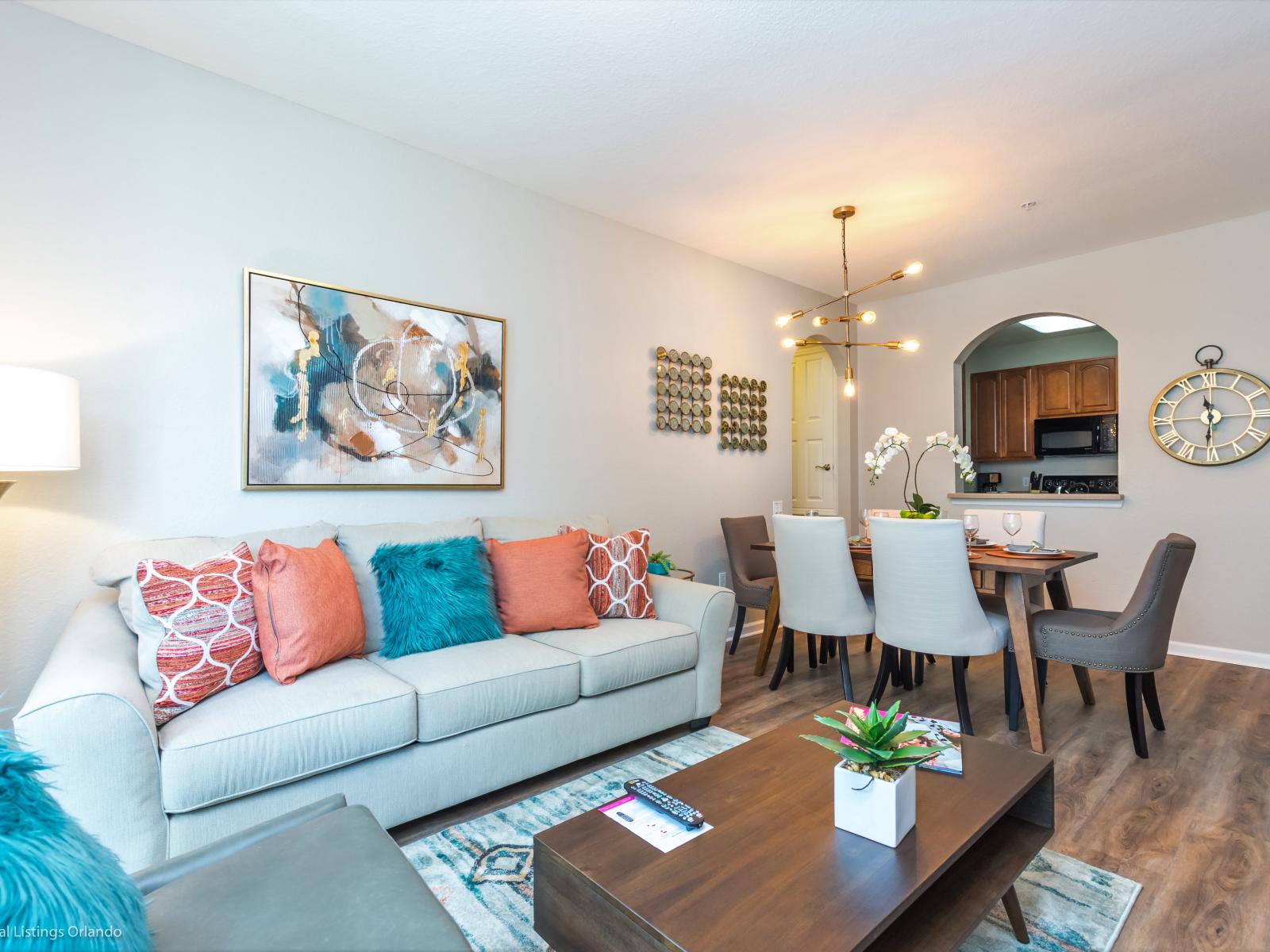 Next to the dining room is the  vibrant living room featuring a cozy sofa adorned with colorful throw pillows, adding a lively touch to the space.