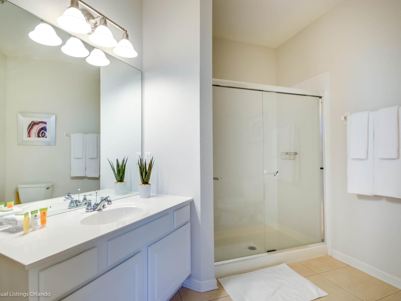 Elegant bathroom of the condo in Orlando Florida - Contemporary fixtures for a touch of indulgence - Sophisticated color palette creating a serene ambiance - Walk-in shower stall - Chic design featuring a sleek vanity and upscale lighting