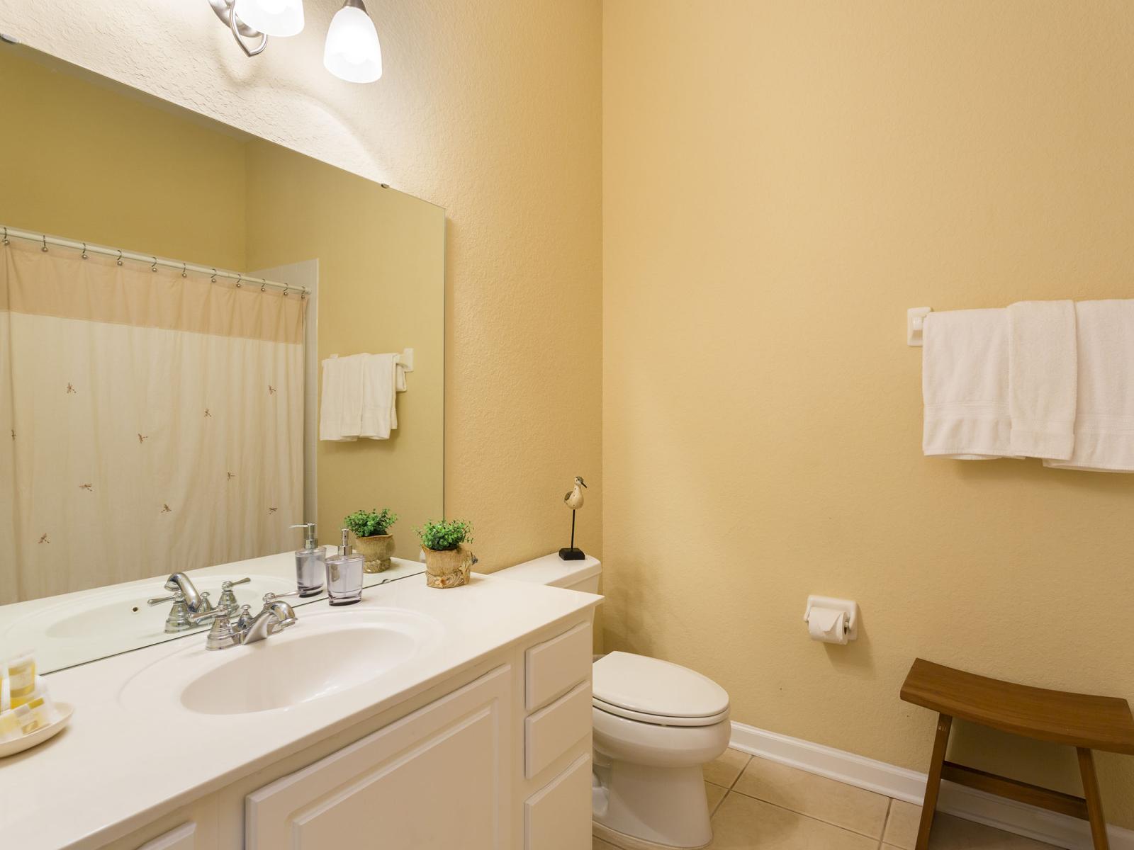 Classy bathroom of the condo in Orlando - Glorious vanity with large size wall mirror and plenty of storage space - Neat and clean cozy toilet seat - Fresh towels available - Separate walk-in shower area with sliding curtains