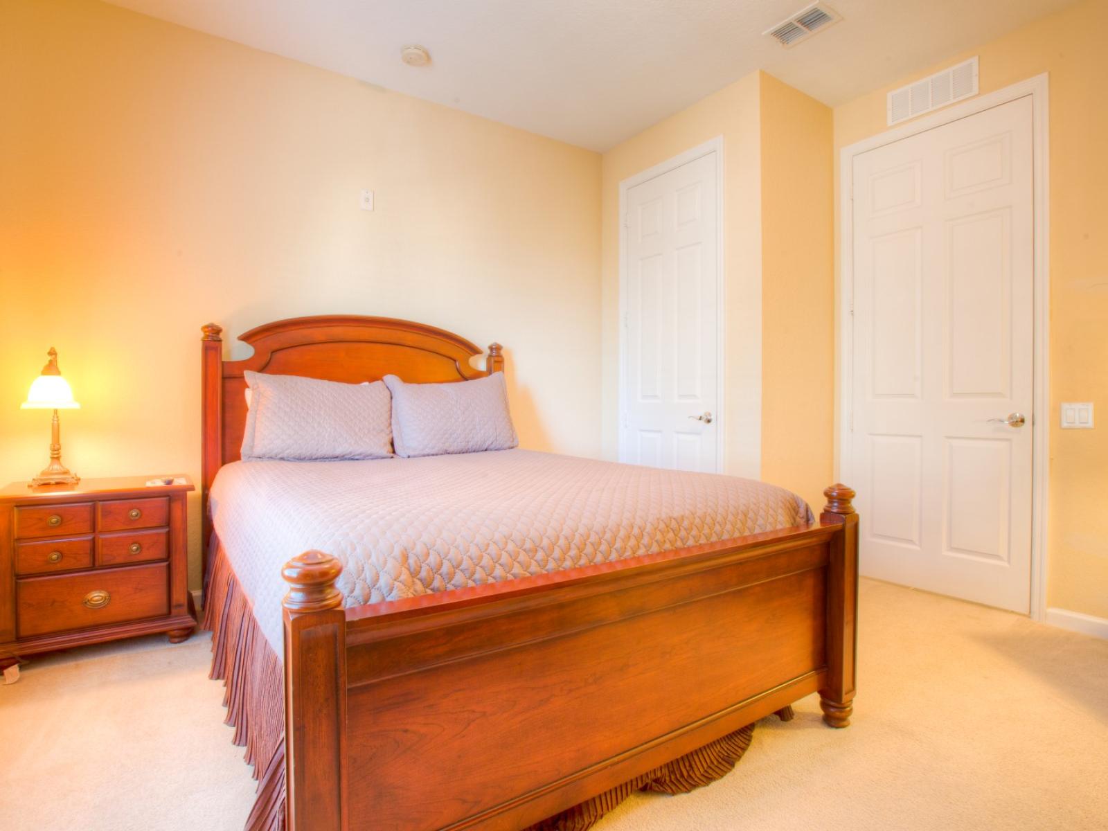 This bedroom, complete with a cozy side table and lamp, creates a soothing retreat where the gentle glow invites relaxation and bedtime stories unfold in the comfort of your own personal haven.