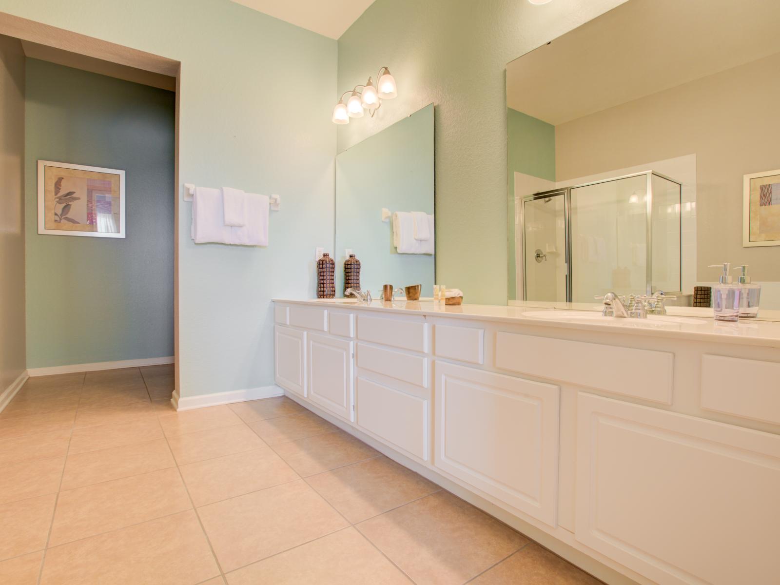 - Classy bathroom of the condo in Orlando - Lovely twin sink vanity with big wall mirrors - Neat and clean toilet seat - Availability of all bathroom amenities - Well designed glass enclosed shower area to keep yourself fresh and warmth