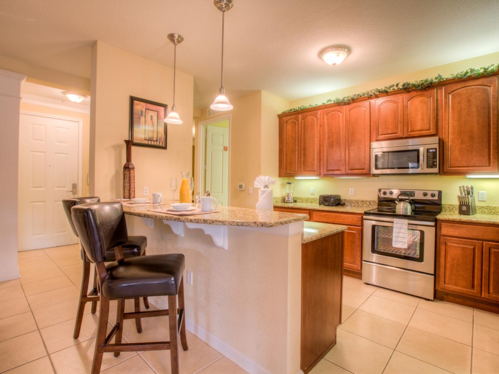 Sleek kitchen of the condo in Orlando -  With stylish design and wooden cabinets with sufficient storage space - Glorious bar counter with availability of high chairs - Smooth lighting - Fully equipped with all kitchen accessories