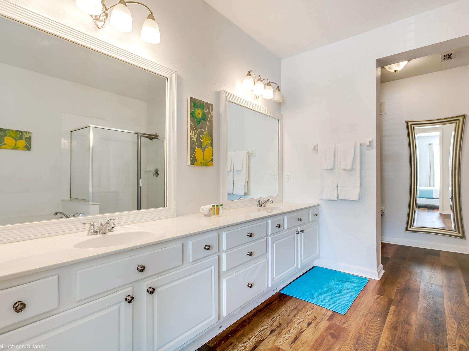 Luxury Spa-like bathroom of the condo in Orlando - Glorious space with relaxation and modern design come together - Grand vanity with twin sink and big size wall mirrors with wall lamps - Plenty storage space - Stunning glass enclosed shower area