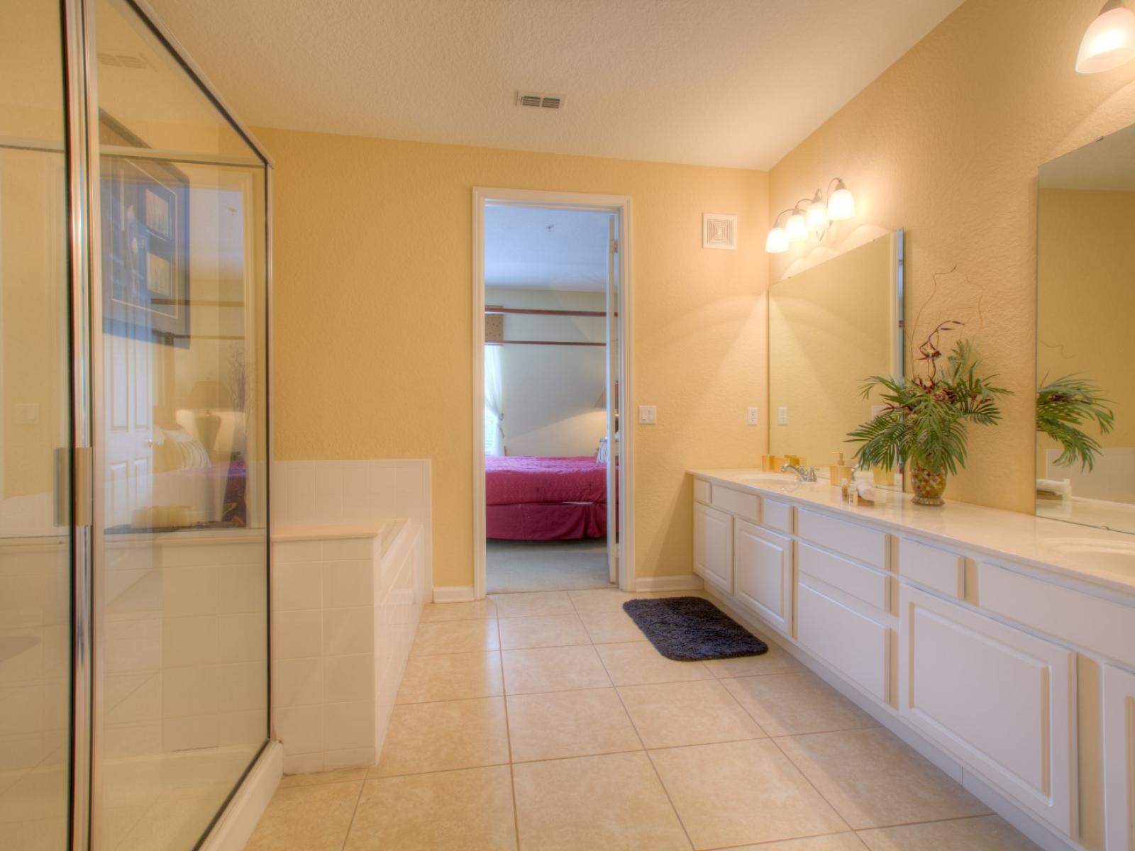 Classy Bathroom of the condo in Orlando - Glorious vanity with twin sinks and large size wall mirrors with wall lamps - Magnificently designed glass enclosed shower area and cozy bathtub - Sufficient storage space -  Availability of fresh towels