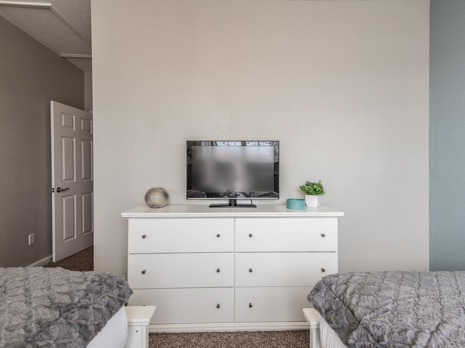 Unwind in this bedroom featuring two beds and a TV, perfect for a comfortable and relaxing stay.