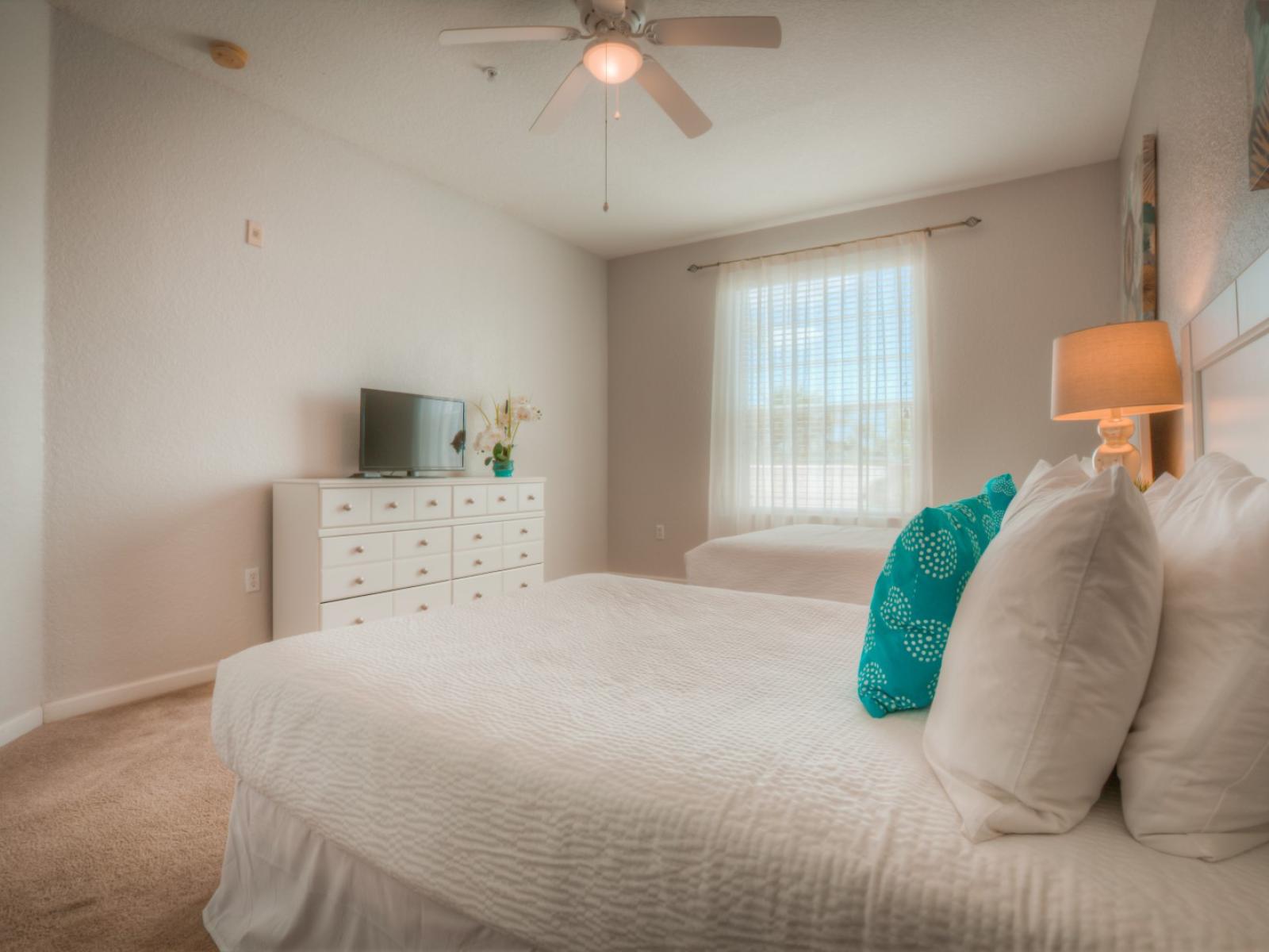 Retreat to this bedroom at Vista Cay Resort, complete with sleek white drawers and a TV, offering guests a cozy and contemporary space to unwind and enjoy their favorite shows in style.