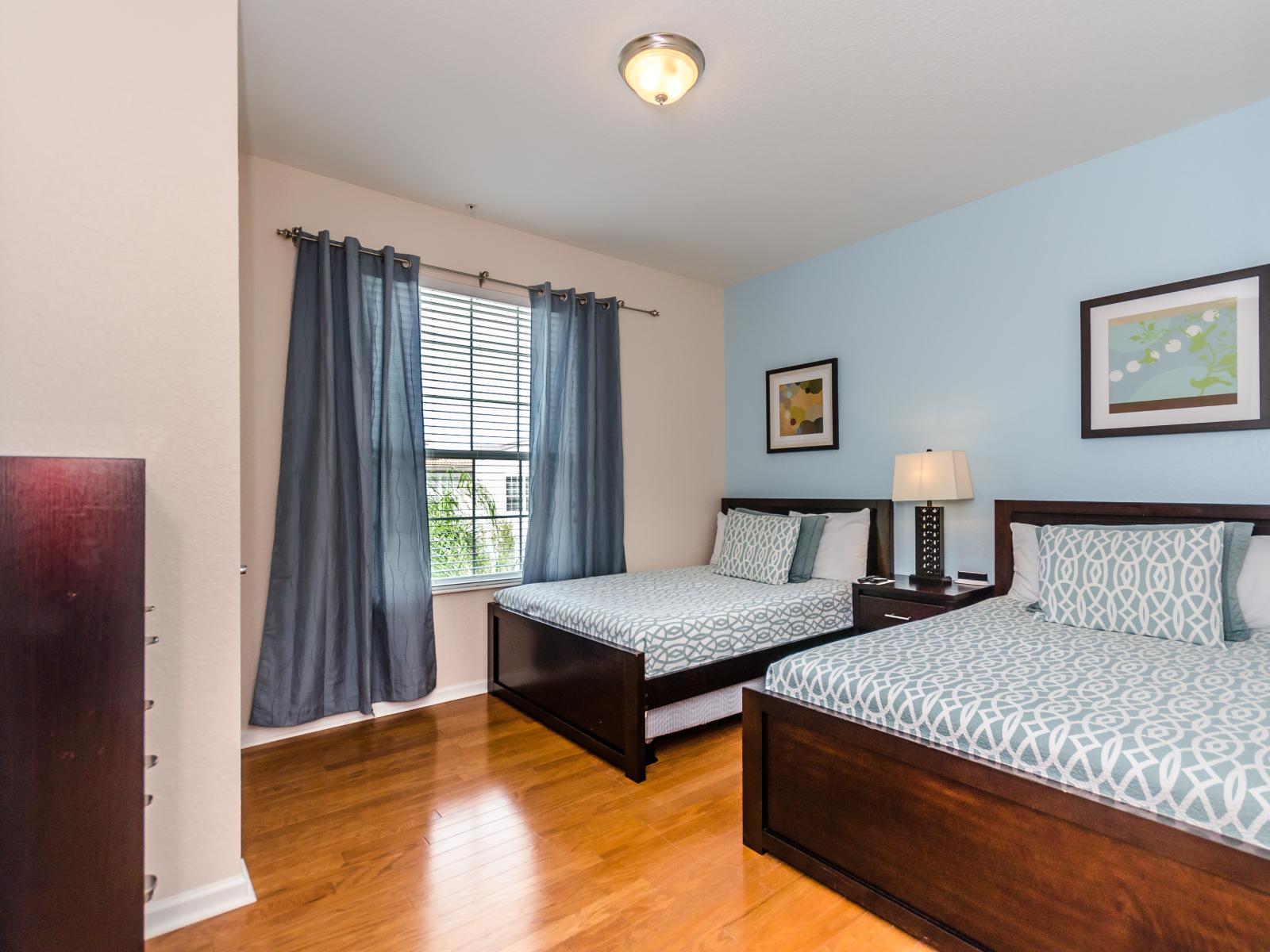 Comfortable bedroom of the condo in Orlando - Featuring two cozy beds perfect for a restful night's sleep - Gloriously appointed bedside window with beautiful views - Stunningly wooden furnished floor