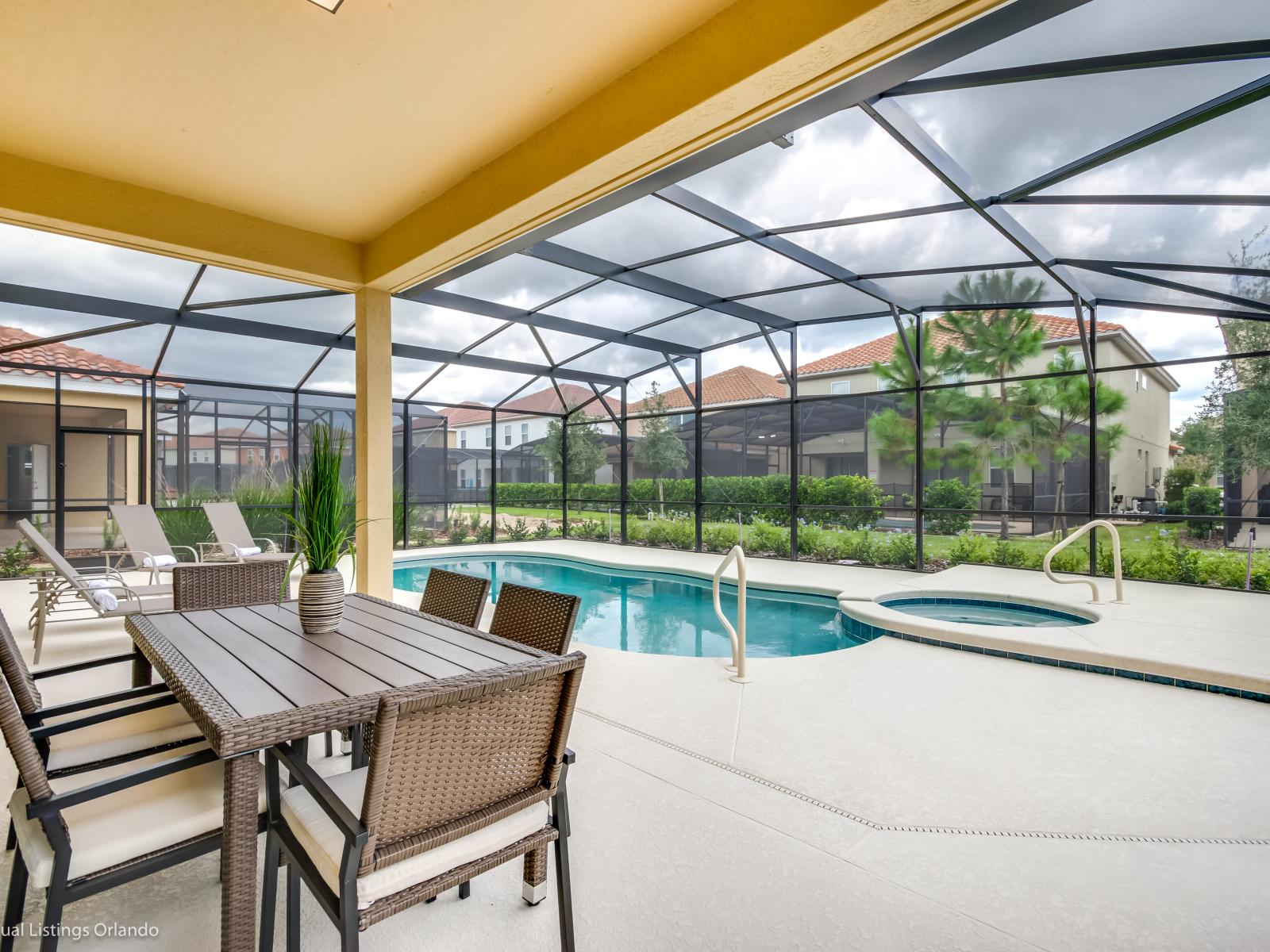 Refreshing outdoor dining area of the home in Davenport Florida - Lounge chairs for ultimate relaxation - Whether it's a cozy meal or a moment of relaxation - Offering a direct view of the sparkling outside pool