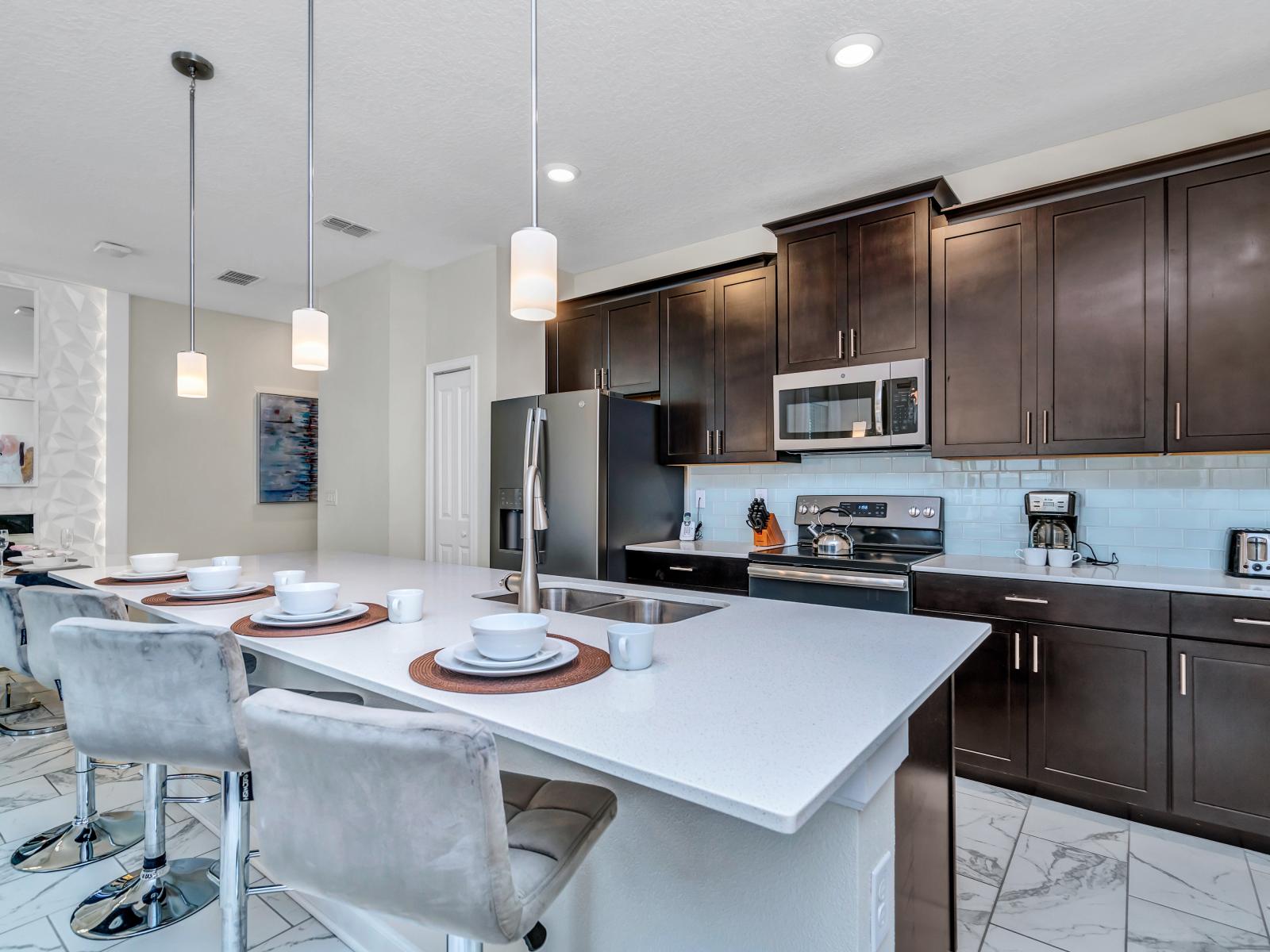 Sleek kitchen of the Townhouse in Kissimmee Florida - Sleek, stainless steel appliances - High Chair and Breakfast bar - Elegant and coordinated color palette for a cohesive look