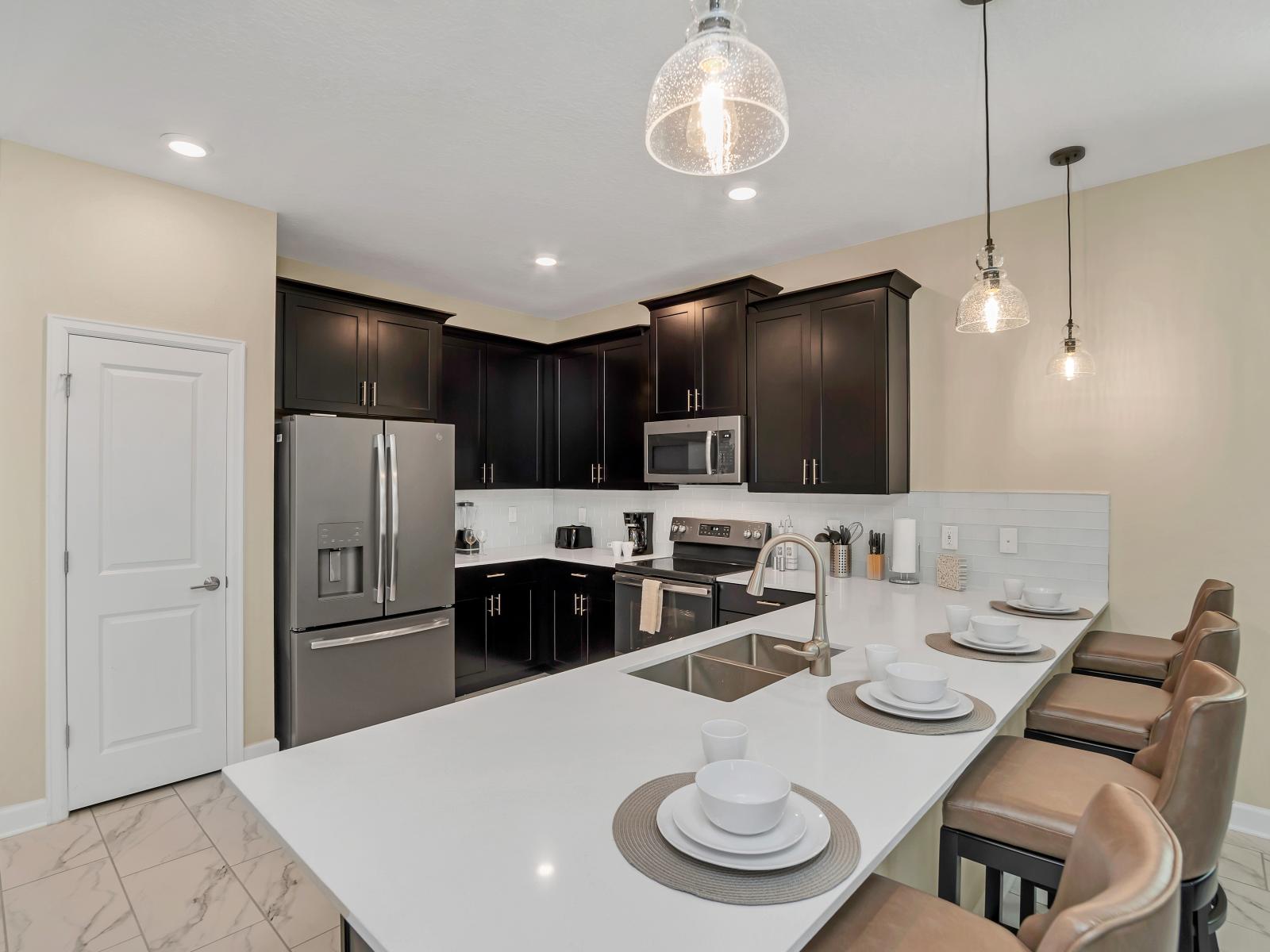 Fully equipped kitchen features modern appliances and barstools at the counter area, allowing you to prepare delicious meals and snacks with ease.