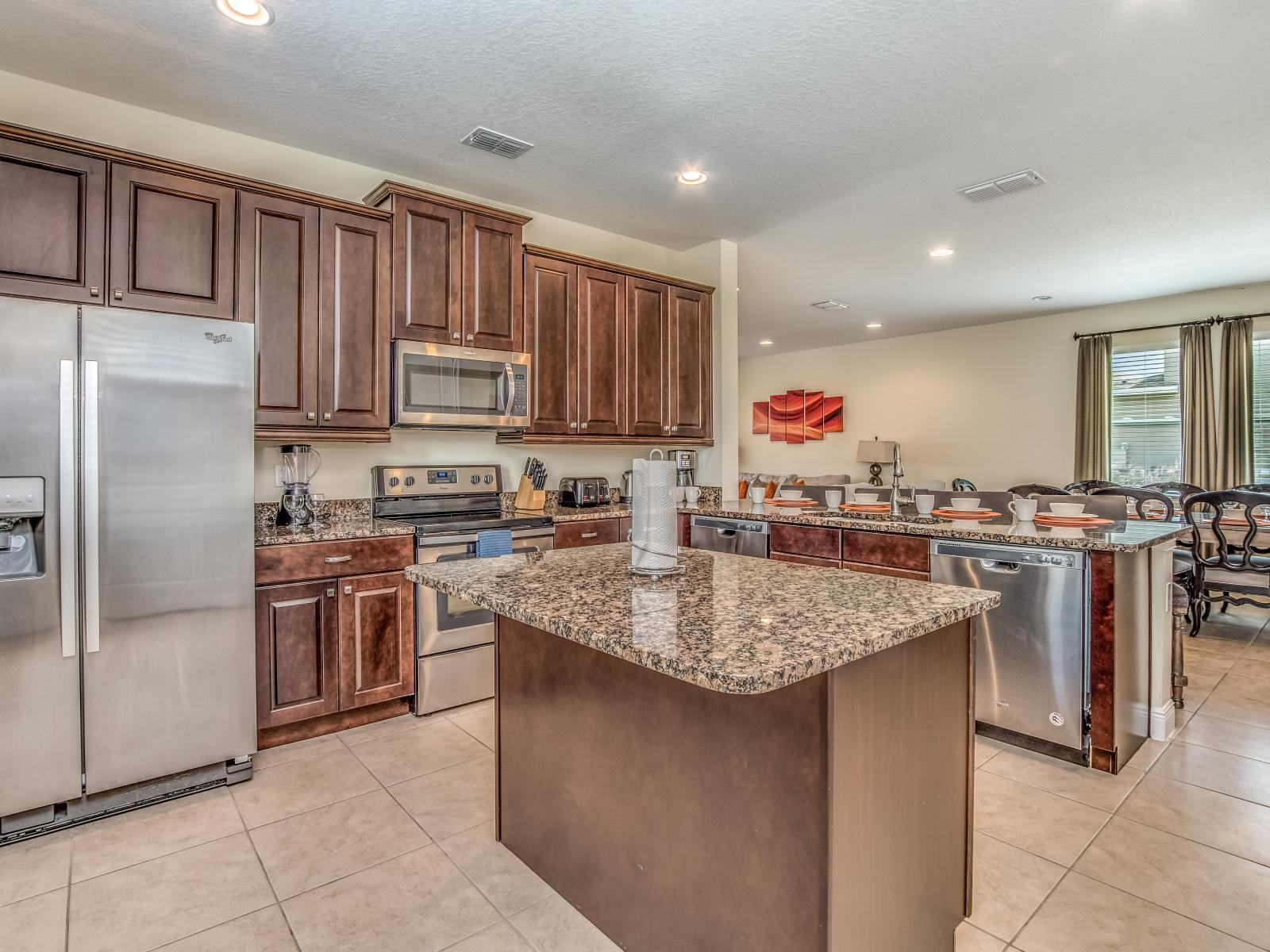 Sleek kitchen of the Home in Kissimmee Florida - Integrated appliances for a seamless and stylish appearance - High Chairs and breakfast bar - Coordinated kitchen decor for a polished and inviting atmosphere