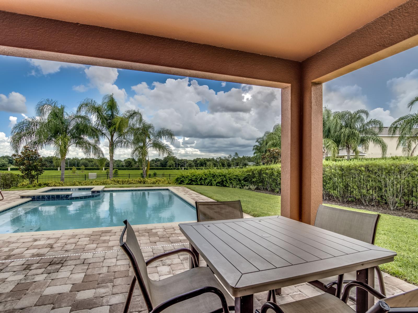 Refreshing Outdoor Dining Area of the Home in Kissimmee Florida - Savor the sunshine and poolside ambiance at the  outdoor table by the pool area - A delightful al fresco experience amidst the refreshing waters and vibrant surroundings