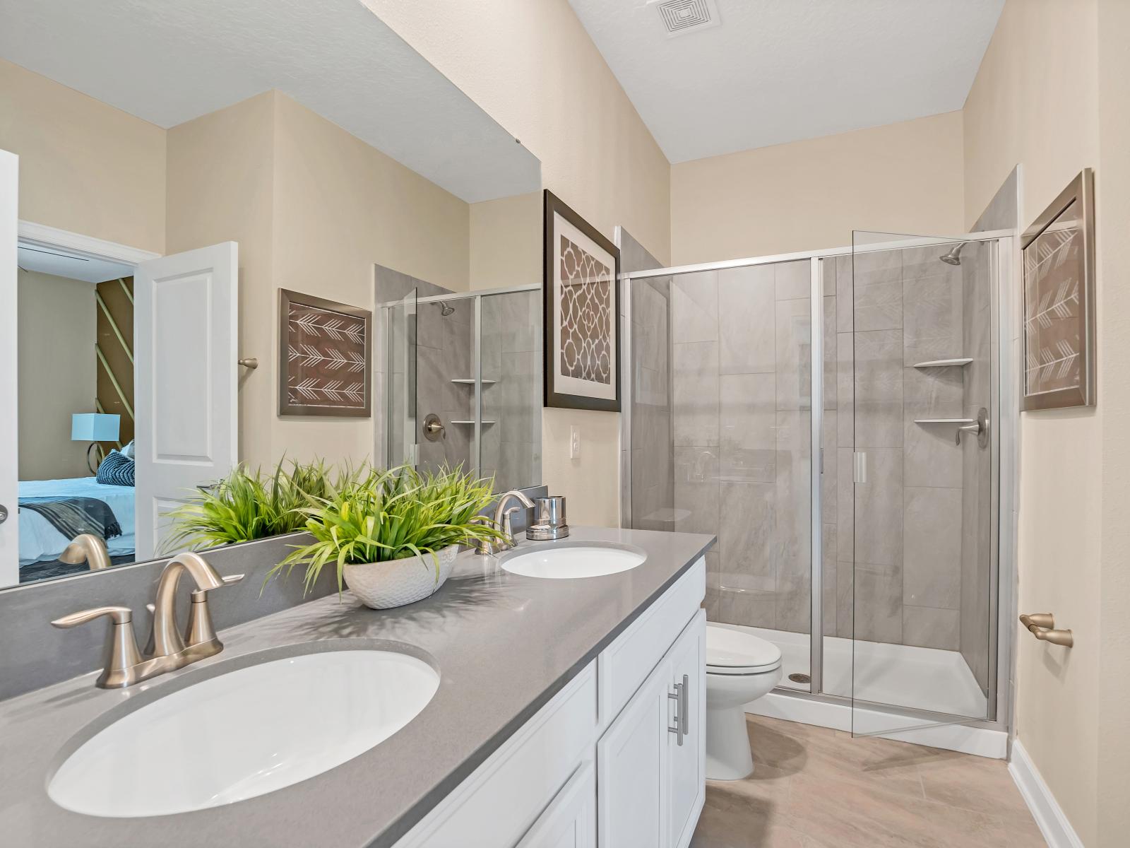 Polished Bathroom of the Home in Reunion Florida - Chic Dual Vanity with large mirror - Stylish glass-enclosed shower area - Contemporary fixtures for a touch of indulgence