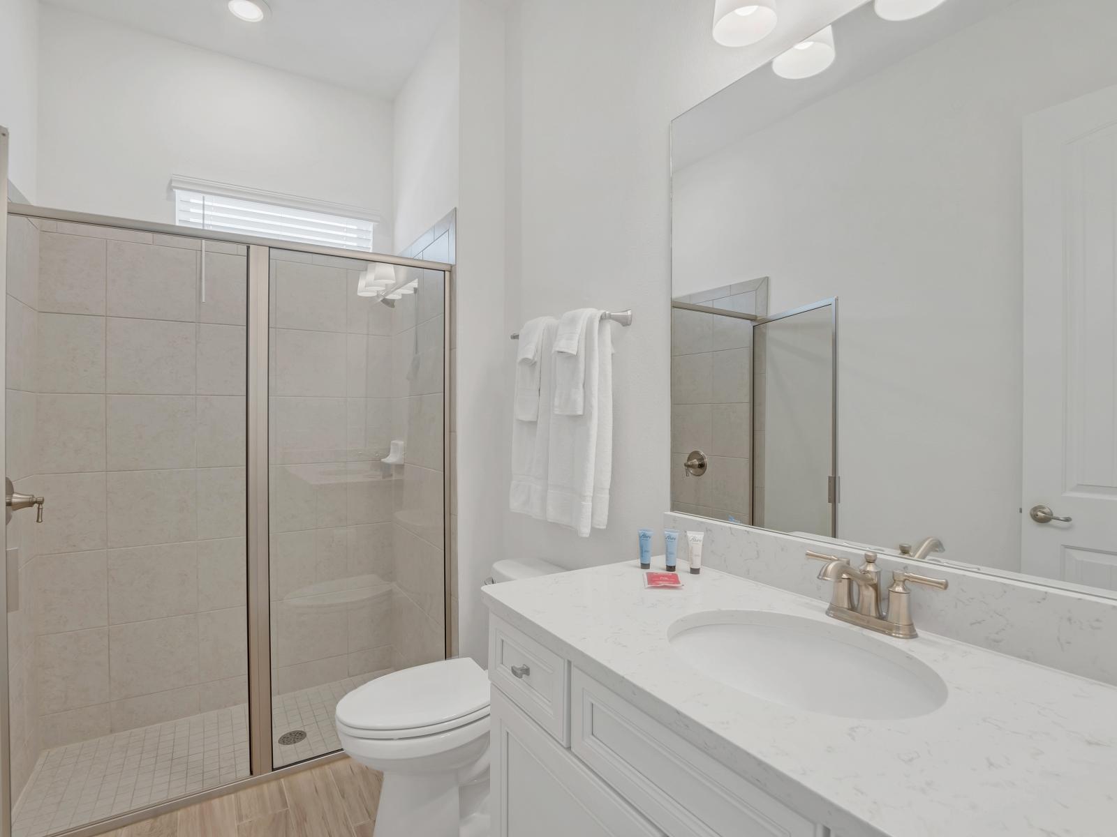 Lavish Bathroom of the apartment in Four Corners. - Beautiful Vanity with large size wall mirror - Sufficient storage space - Neat and clean toilet seat - Availability of all bathroom amenities - Stunning glass cabin shower area