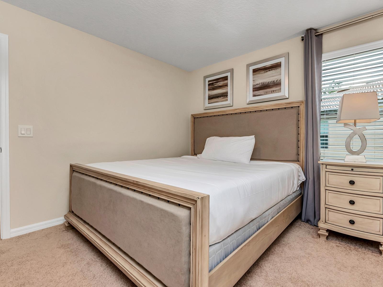 This bedroom, complete with a cozy side table and lamp, creates a soothing retreat where the gentle glow invites relaxation and bedtime stories unfold in the comfort of your own personal haven.