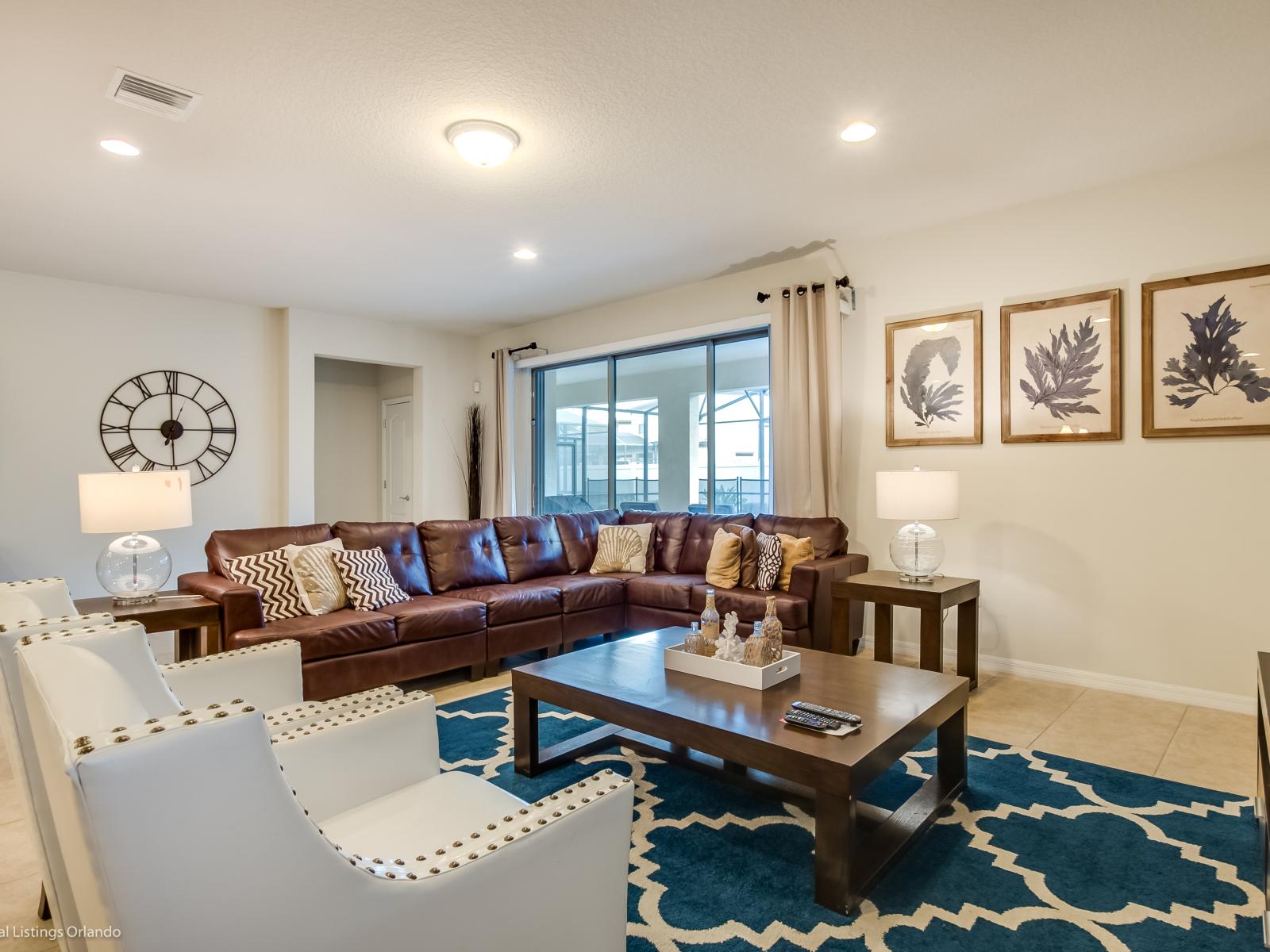 Step into the elegant living area adorned with a plush brown couch and complemented by white accent chairs. A harmonious blend of comfort and style, promising refined relaxation and timeless charm in every corner.