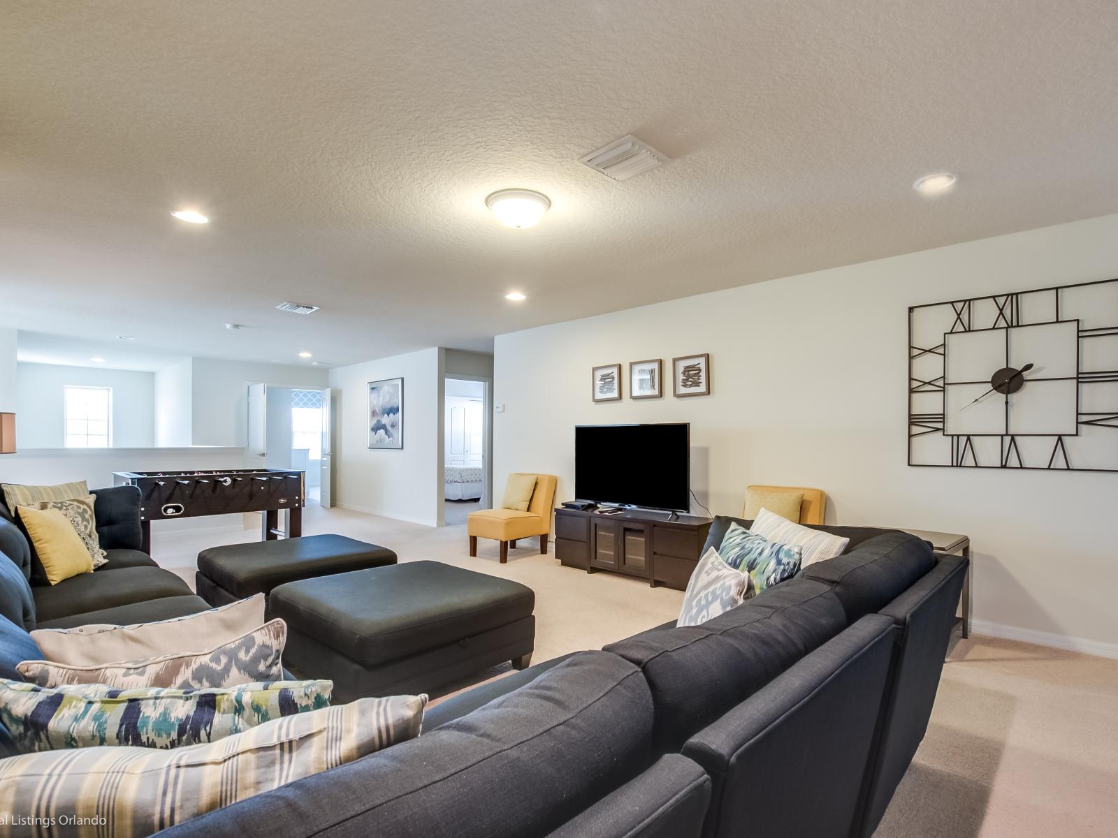 Ascend to the second-floor loft area, where another realm of relaxation awaits. With a sprawling sectional couch, a large flat-screen TV, foosball table, and a convenient wet bar, indeed it's the ultimate hang-out space.