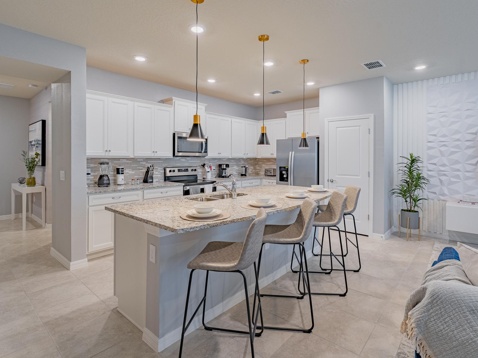 Spacious open concept kitchen of the home in Davenport, Florida - Kitchen adorned with white details and accents, exuding a sense of crisp elegance - Breakfast Bar with high chairs - Strategic space optimization with versatile storage solutions