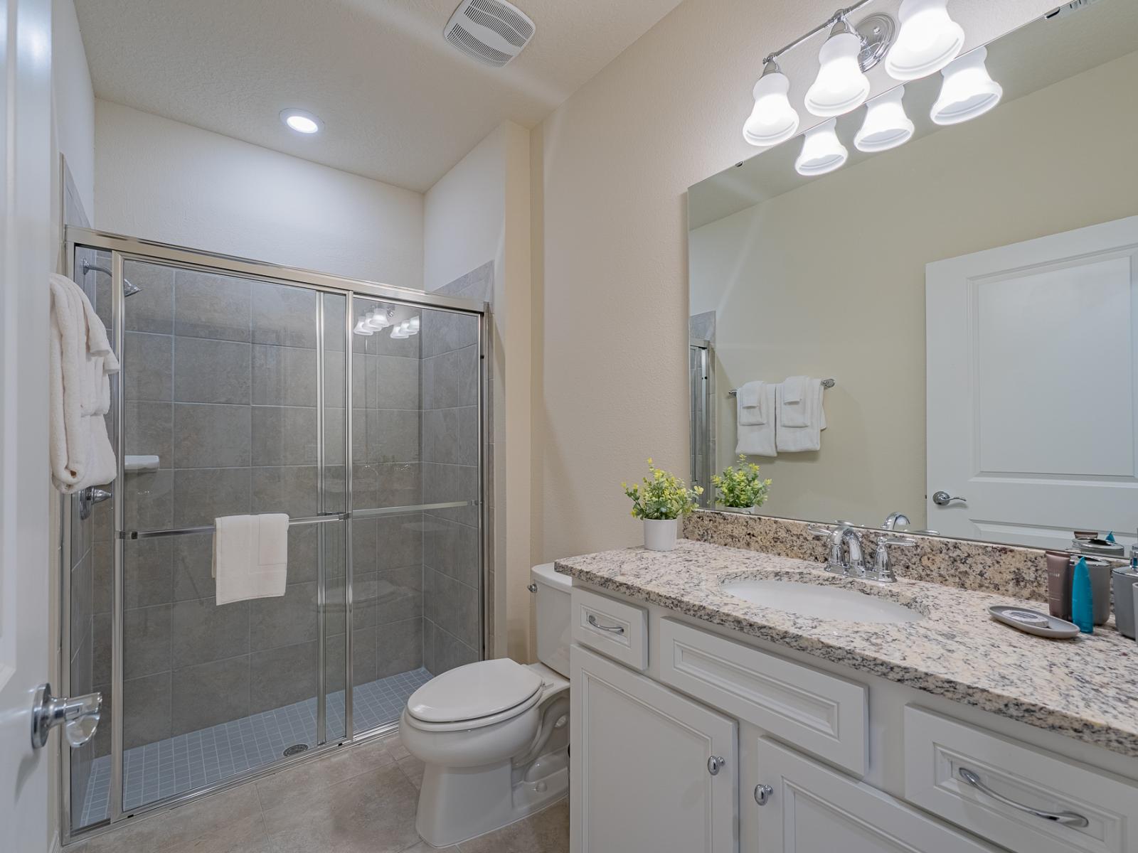 Classy bathroom of the home in Davenport, Florida - Bathroom featuring a sleek shower enclosure, epitomizing contemporary comfort and style - Glamorous vanity adorned with a sizable mirror and abundant storage space