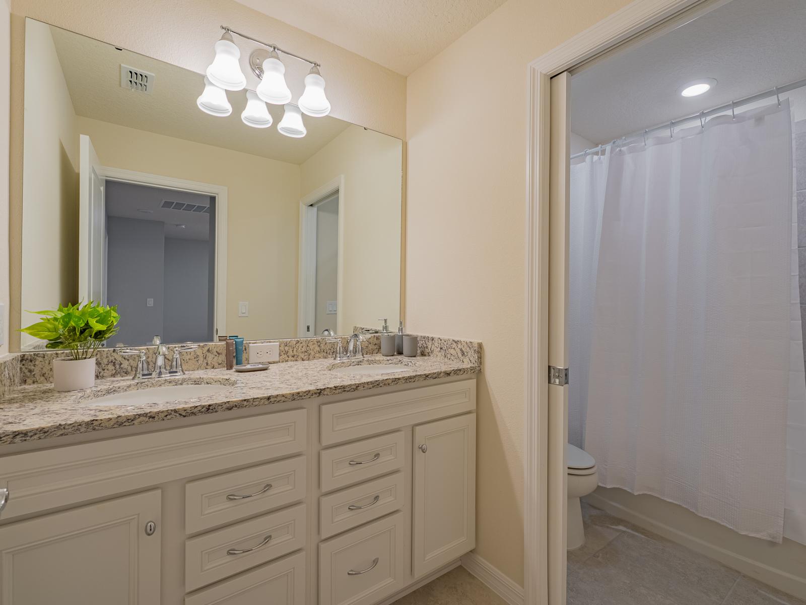 Lush bathroom of the home in Davenport, Florida - Gorgeous vanity with oversized wall mirror with Stunning lighting - Separate Shower alcove with sleek sliding curtains - Sophisticated charm highlighted by sleek lines and intricate details