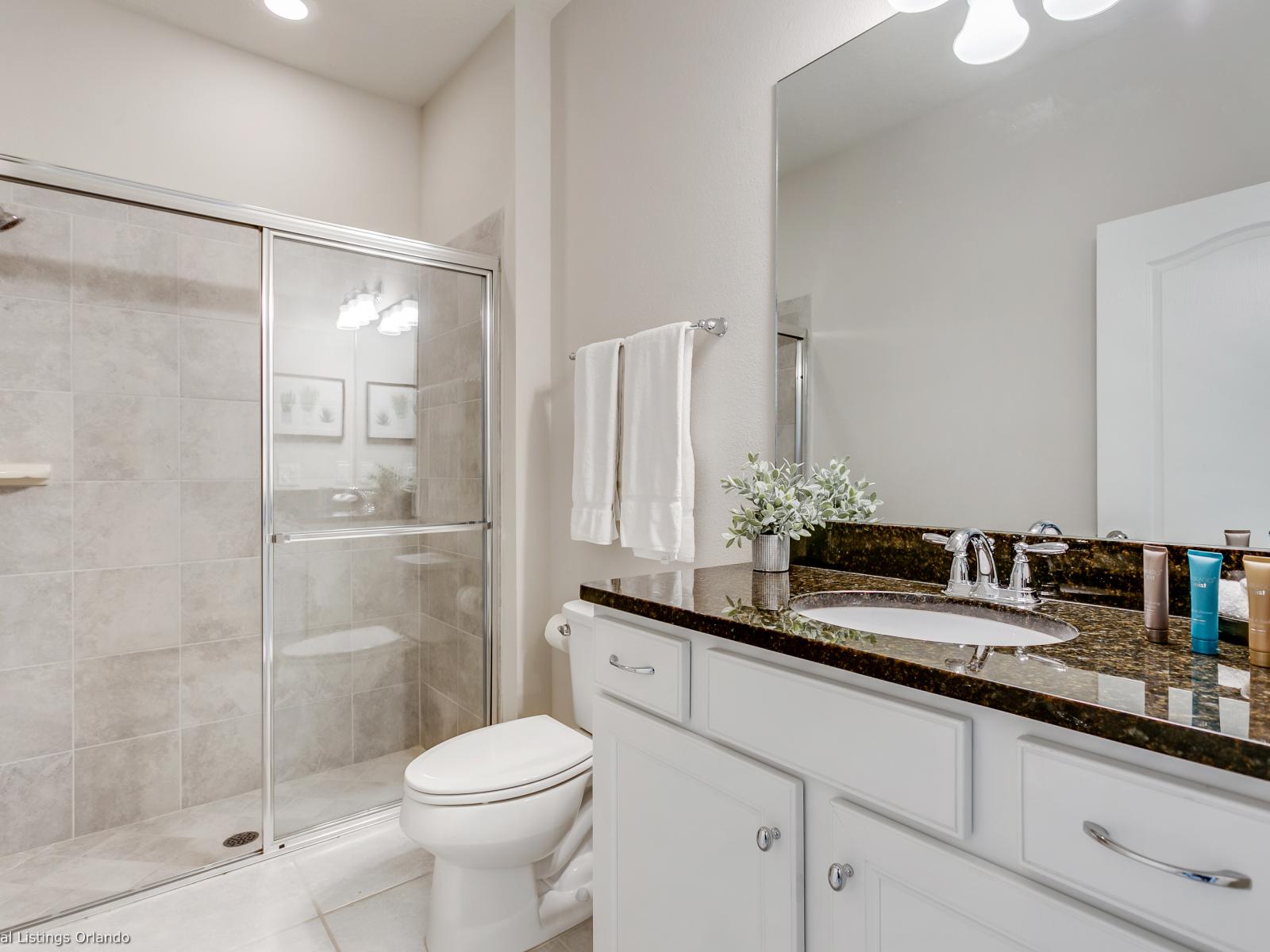 Polished Bathroom of the townhouse in Kissimmee, Florida - Transform your shower into a luminous sanctuary with a sleek glass-covered enclosure - Stylish Vanity with large mirror and plenty of space