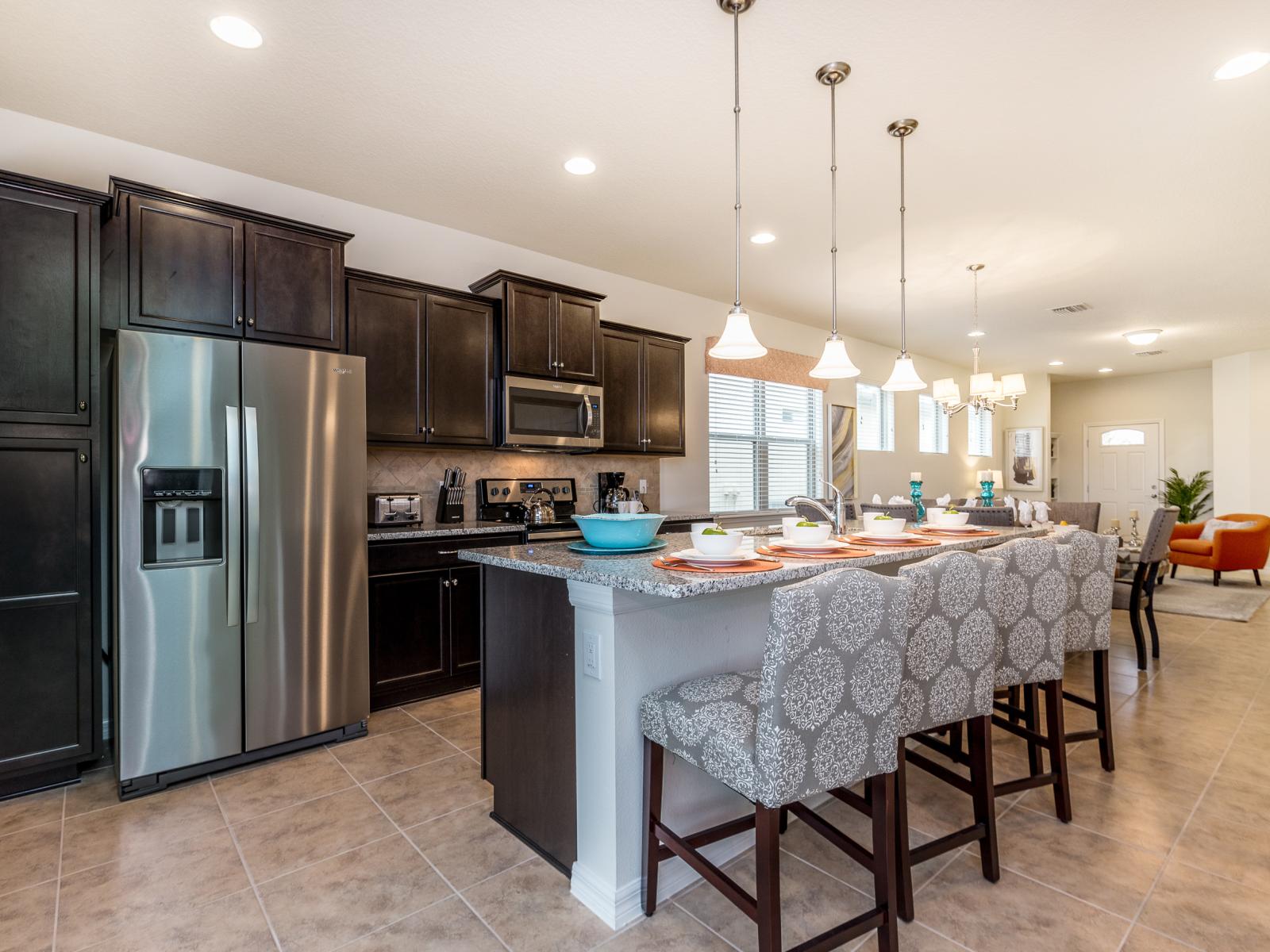 The kitchen, complete with a sleek counter bar table, transforms into a culinary hub where flavors mingle and conversations flow.