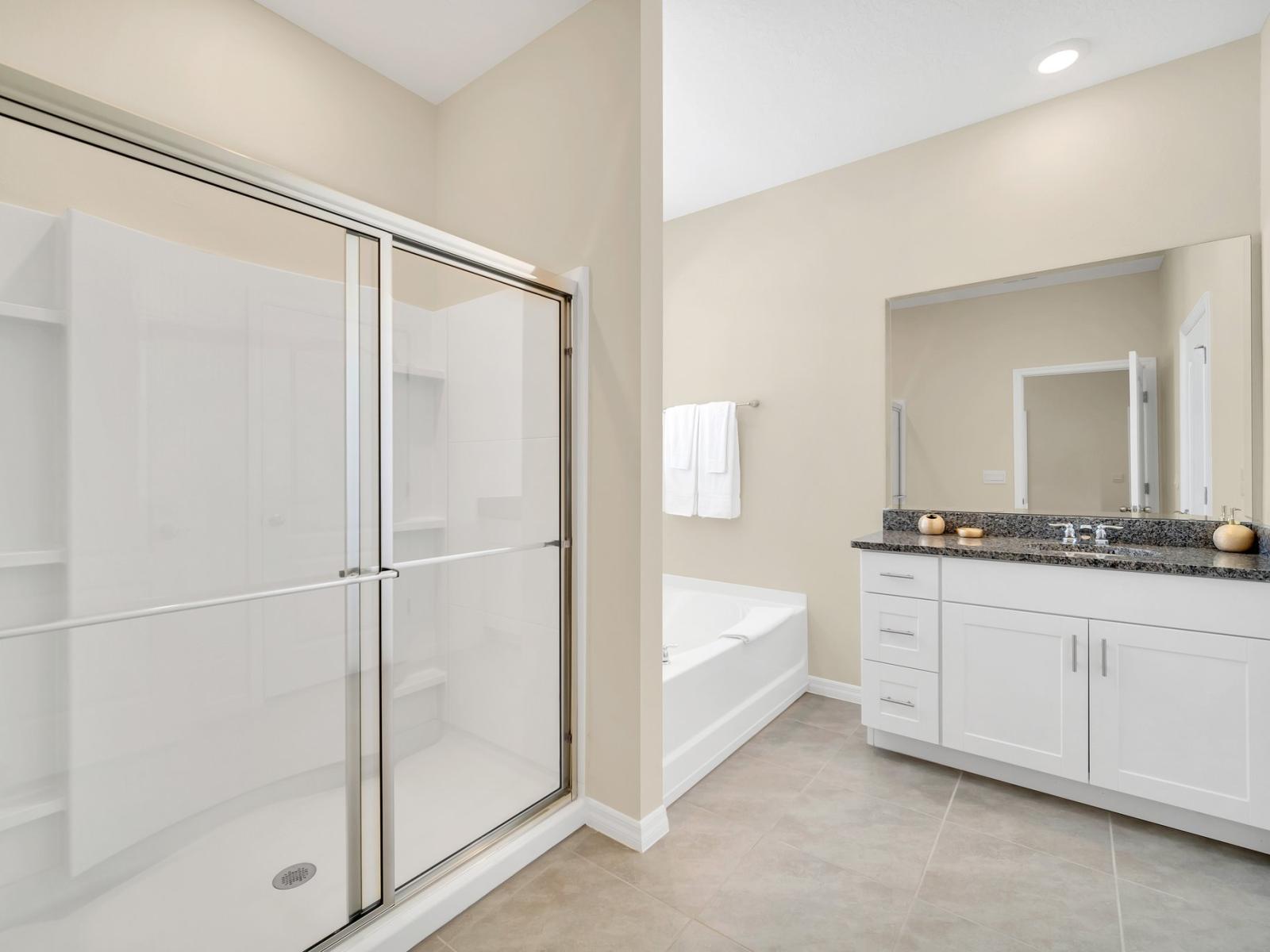 Polished bathroom of the home in Florida - Inviting bathroom with a soothing color palette for a tranquil feel - Spacious shower stall with sliding glassdoor - Separate spa alike bathtub - Chic vanity with large mirror