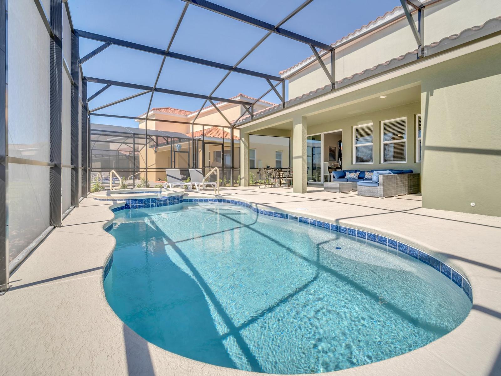 Step into the inviting private screened-in lanai, designed for both entertainment and relaxation, featuring comfortable outdoor furniture, a deluxe dining table, poolside loungewear, and your personal spa and pool facilities.