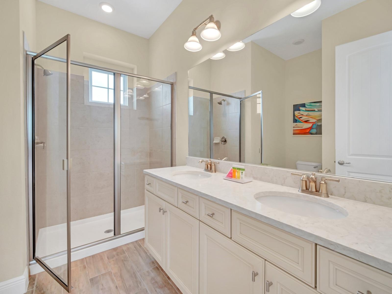 - Polished bathroom of the cottage in Reunion Florida - Indulge in the serenity of glass-enclosed shower area - Complete with a spacious vanity space for your grooming essentials - Sophisticated color palette creating a serene ambiance