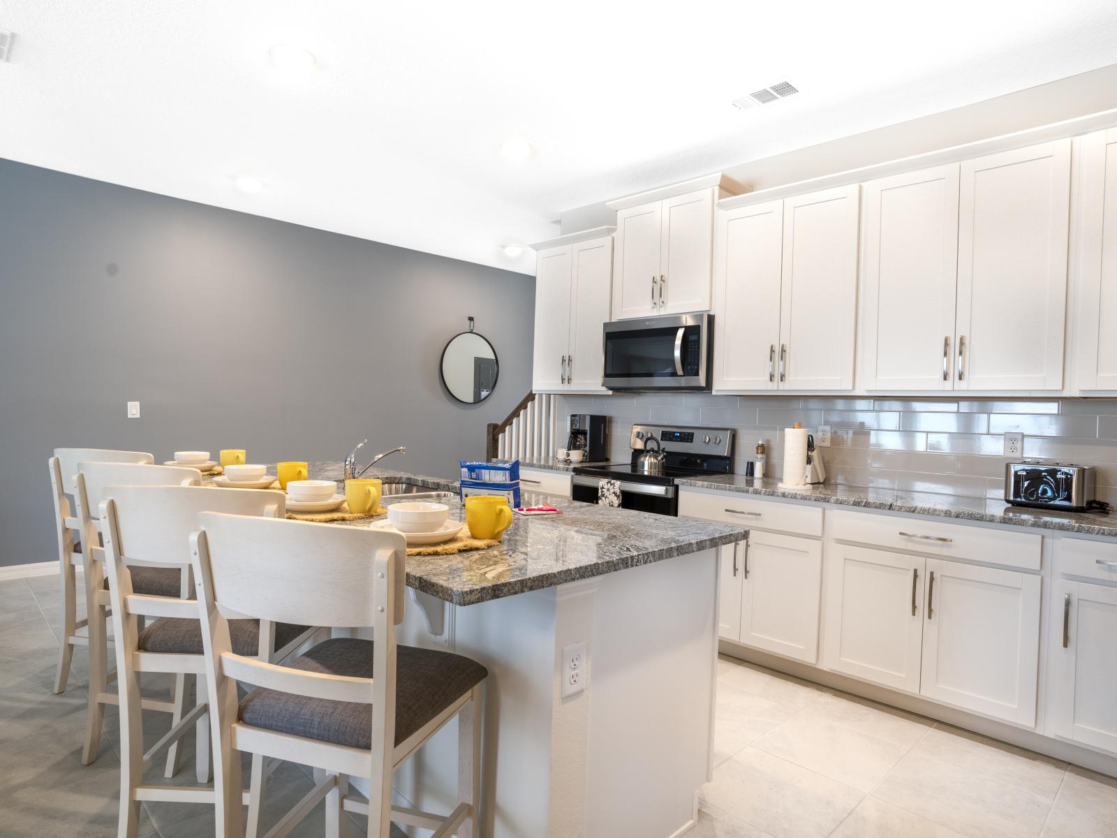 Fully equipped kitchen of the townhouse in Four Corners Florida - Features modern stainless steel appliances - Breakfast bar and high chairs - Open concept connecting the kitchen to the dining area