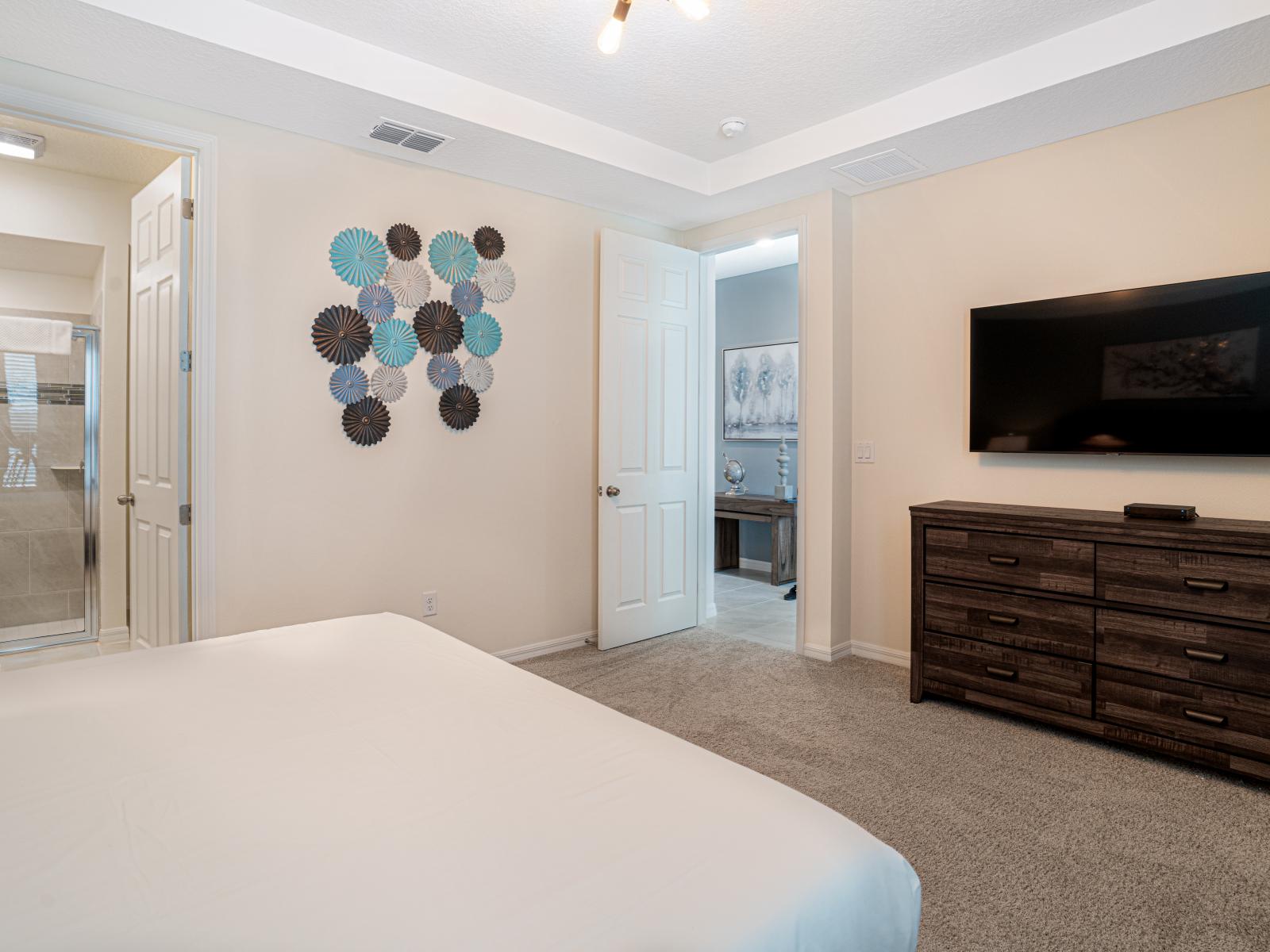 The second bedroom presents a sophisticated yet welcoming atmosphere, featuring a queen size bed adorned with a contemporary tufted headboard and elevated base, all resting upon an elegant frame.