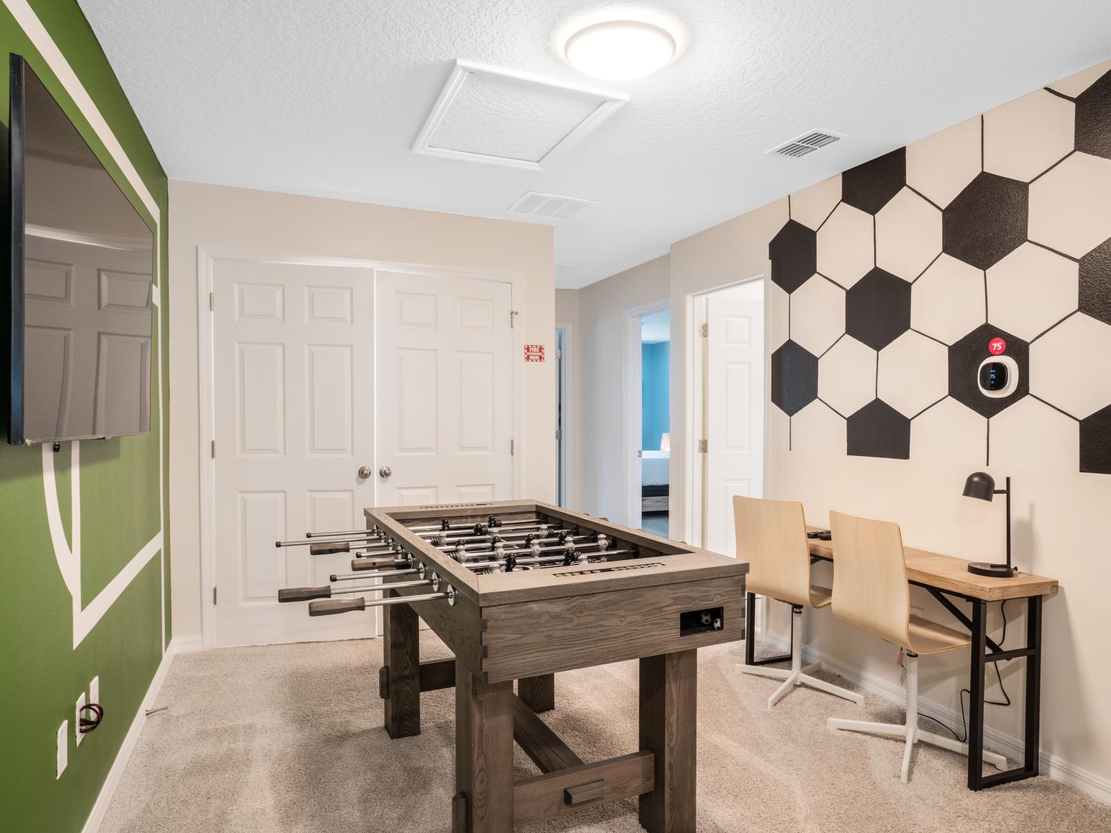 Wide open space game room with foosball  table as well as a wall-mounted flat-screen television, perfect for fun-filled activities for the whole family.