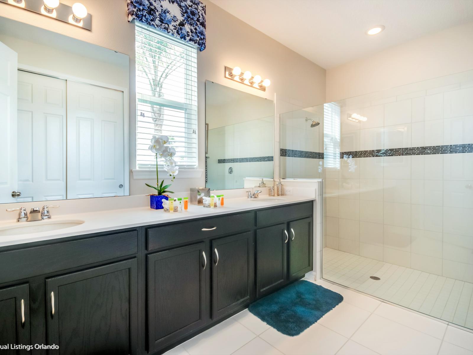 Polished bathroom of the villa in Kissimmee Florida - Elegant bathroom with luxurious fixtures and finishes - Chic design featuring a sleek dual vanity and upscale lighting - Glass enclosed spacious shower area