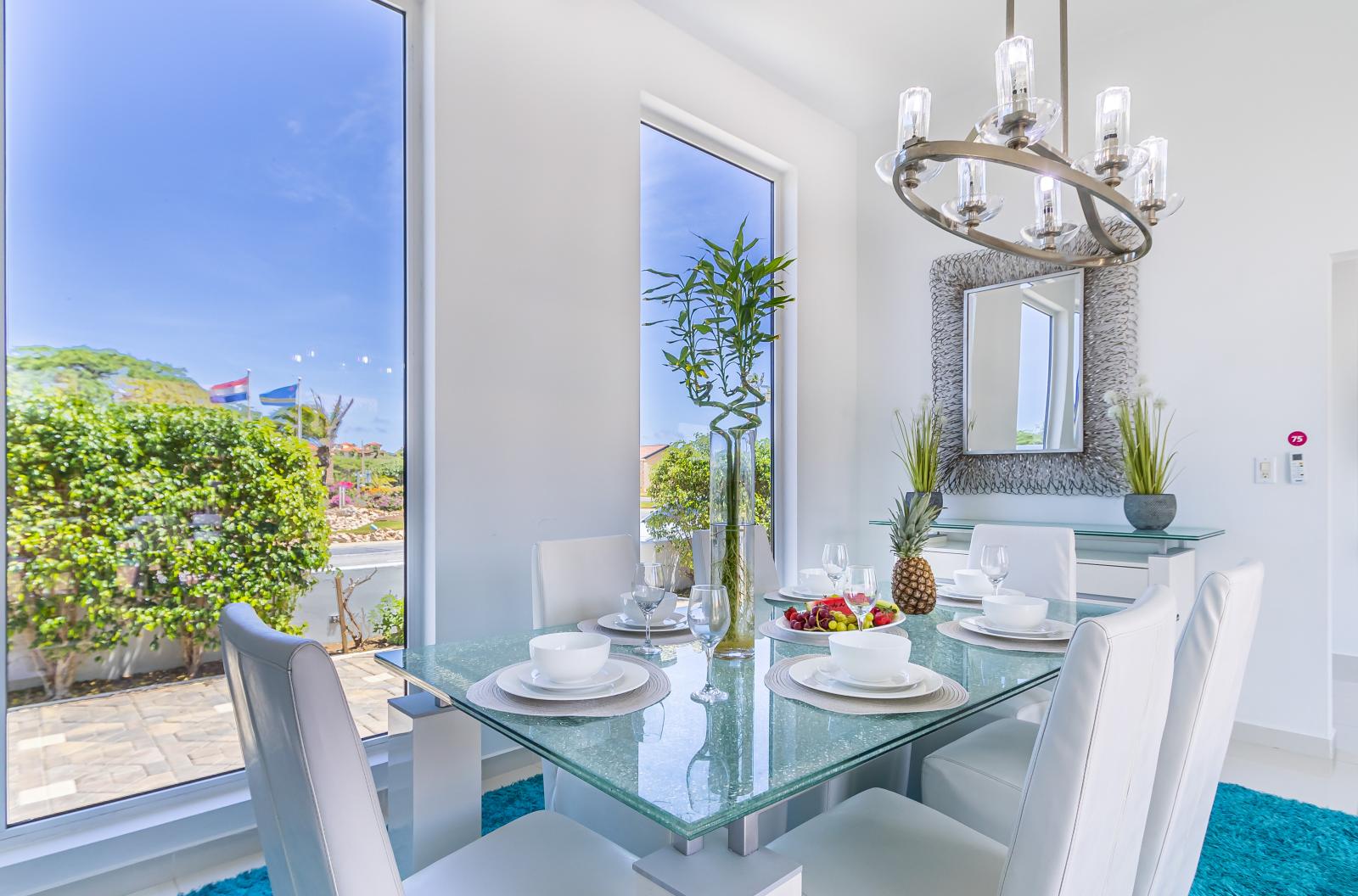 A chic glass top dining table with six high backed chairs