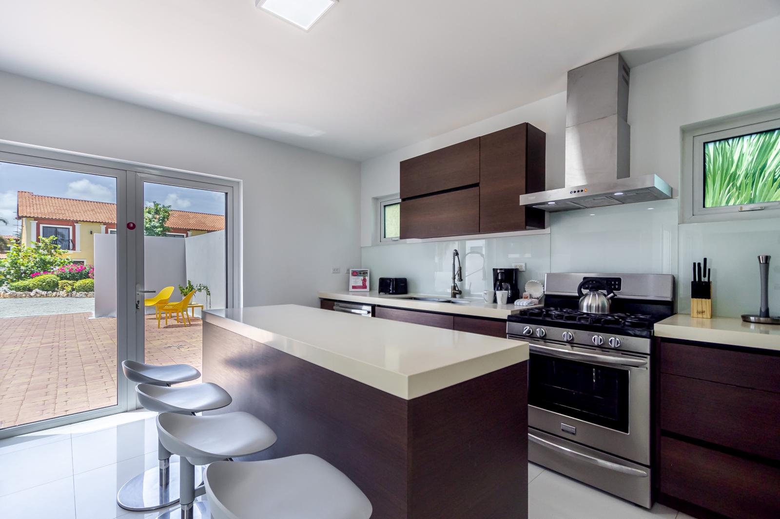 Modern Kitchen of the 3BR house in Noord Aruba - Well-lit space with strategically placed task lighting - Elegant and coordinated color palette for a cohesive look - Fully Equipped - Breakfast Bar with Bar Chairs