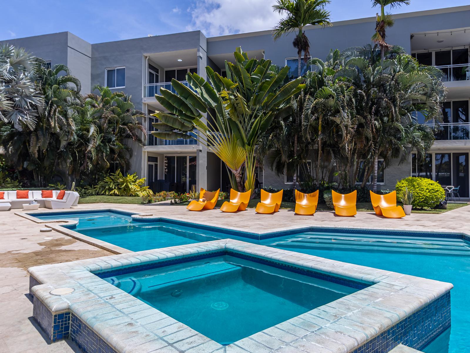 Luxe Shared Pool Area in Oranjestad Aruba - Hot Tub - Relax by the shimmering poolside oasis - Palm trees and tropical plants enhance the vacation feel - Comfy seating Arrangements