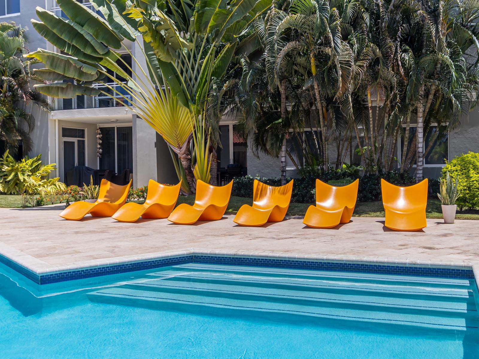 Shared pool with lots of chairs to lounge in the sun