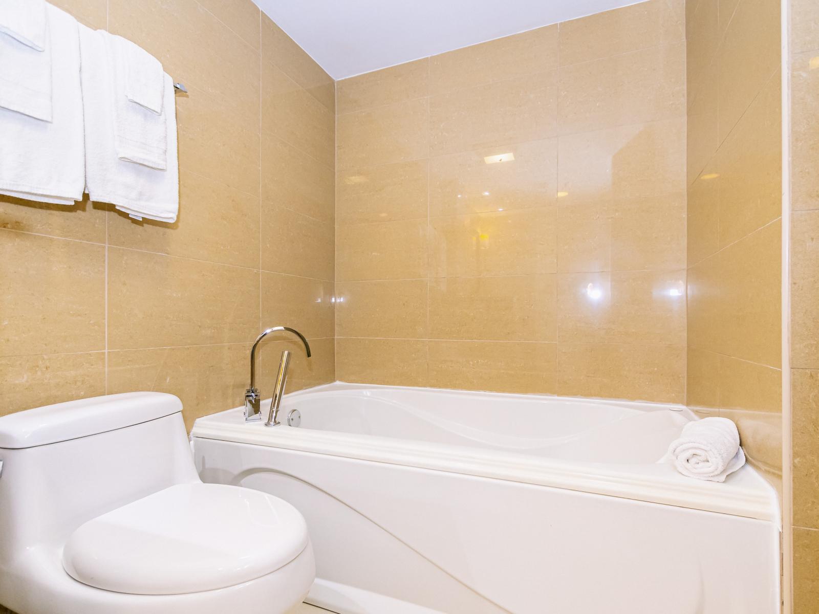 Escape into relaxation in our serene Main Bathroom, featuring a soothing bathtub that invites you to unwind and rejuvenate.