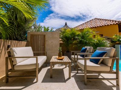 Graceful Outdoor seating Area of the 2BR Home in Noord Aruba - Extended living space for outdoor enjoyment - Lush Pool vies - Find tranquility surrounded by greenery and nature