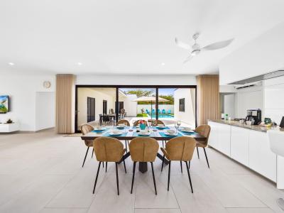 Thoughtfully organized dining area of the home in Noord, Aruba - Stunning 8 persons dining table in front of the open kitchen - Beautifully decorated space with lovely wall paintings - Big and bright doors leading to the backyard