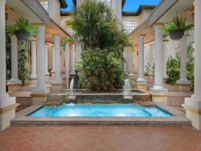 - Tranquil backyard featuring a fountain surrounded by lush greenery and classical columns - A serene oasis perfect for relaxation, blending nature with elegant architecture - The soothing sound of water enhances the peaceful ambiance of the space