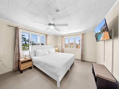 Drift off to sleep amidst refinement in elegant bedroom of the home in Noord Aruba - Your perfect haven offering king size comfy bed and beautiful outside views - Harmonious color palette creating a soothing atmosphere, smart TV for entertainment