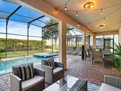 Cozy lounging space under a covered patio, ideal for relaxation and socializing - Stylish outdoor furniture by the private pool with comfortable cushions for added comfort - Overlooks the pool and backyard, providing a tranquil retreat