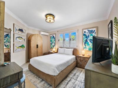 - Cozy bedroom with a plush queen-size bed and calming coastal-themed artwork - Natural light filters through windows, highlighting the earthy tones - Thoughtful details like a wooden wardrobe and decorative plants enhance the room's serene vibe