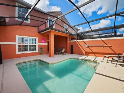 - Private pool area with a screened enclosure, perfect for swimming under the sun - Vibrant orange exterior walls add warmth and character to the space - Comfortable seating and lounge chairs create an ideal spot for outdoor relaxation and dining